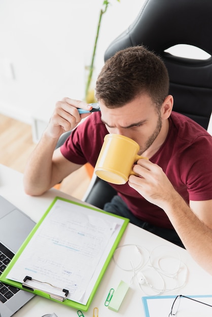 Free photo high view of guy thinking and drinking a coffee