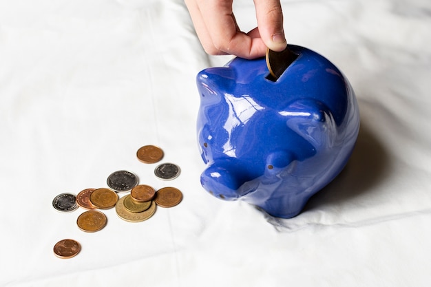 High view hand putting coins in a piggy bank