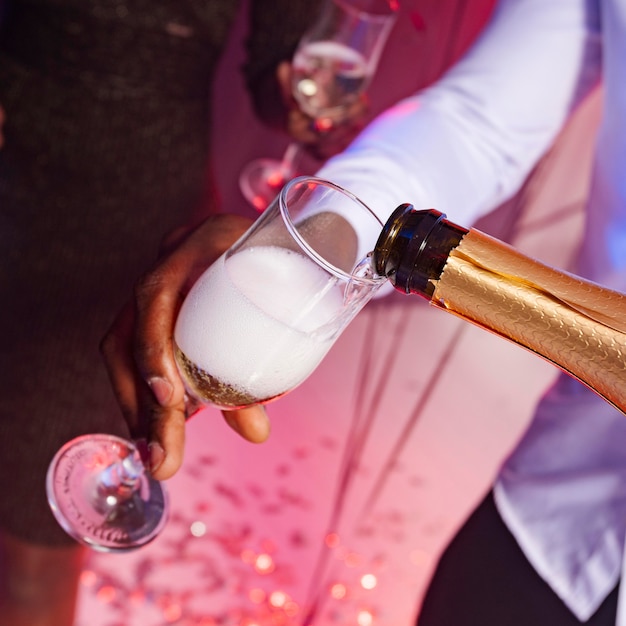 Free photo high view male pouring champagne into a glass