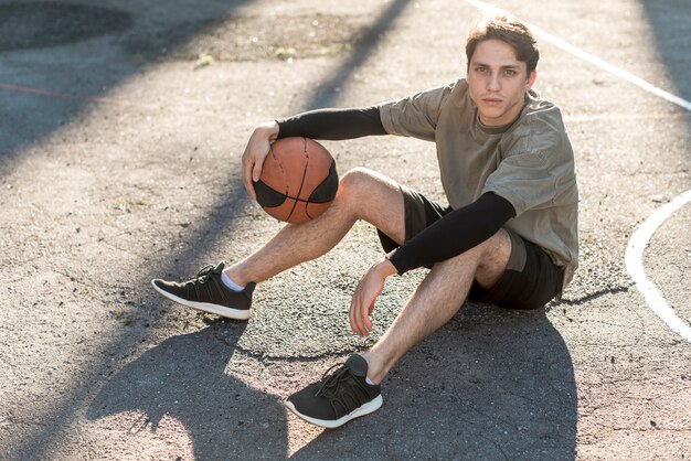 Высокий вид человека, сидящего на баскетбольной площадке