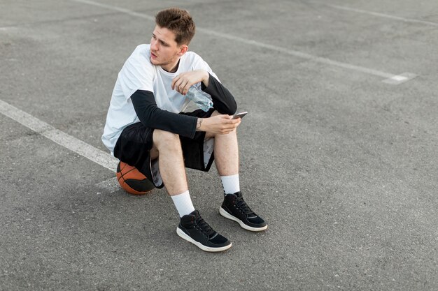 High view man sitting on a basketball