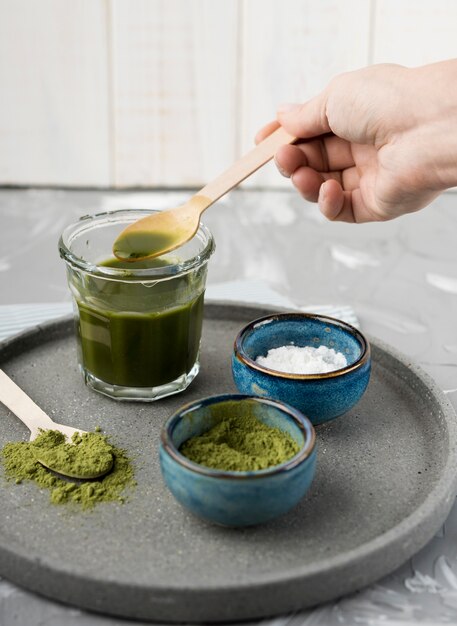 High view matcha tea in glass with herbs in bowls