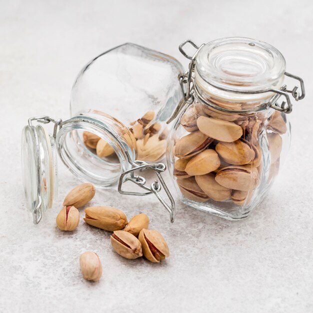 High view overturned jar filled with pistachos on marble table