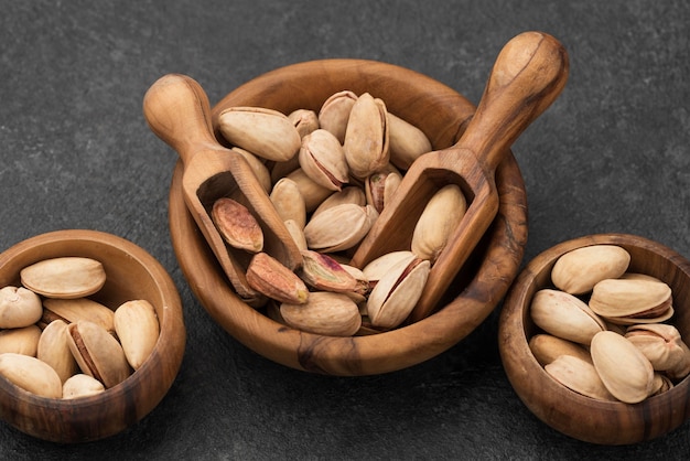 Free photo high view pistachio nuts in bowls with wooden spoons