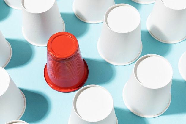 High view red plastic cup surrounded by paper cups