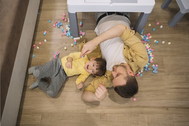 High view son and father laying under the table