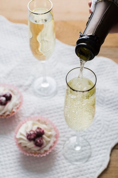 High view white wine glasses and bottle with cupcakes