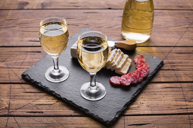 High view white wine glasses and cheese with salami