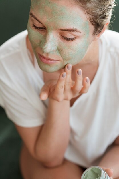 High view woman applying facial mask indoors