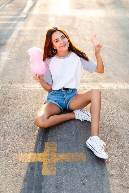 綿菓子を食べて道路に座っている高いビュー女性