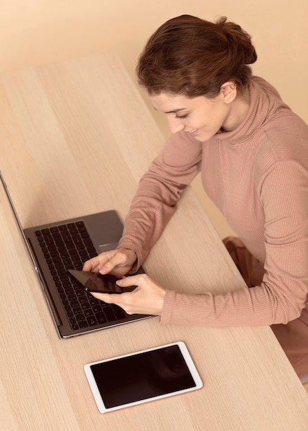 Free photo high view woman sitting next to various digital devices