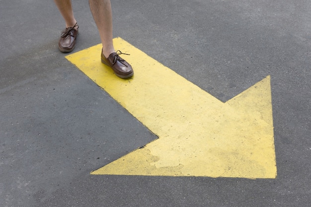 High view yellow painted arrow in the streets and legs