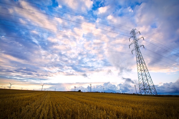 High voltage post with field and sky.