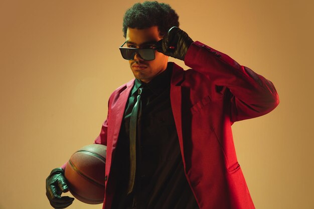 Free photo highfashion styled man in red jacket playing basketball isolted over brown background