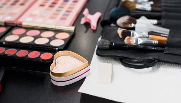 Highlighter powder and makeup brushes on table