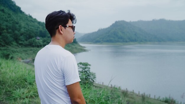 Hiker backpacker man on hiking adventure feeling freedom walking in forest near lake in rainy day