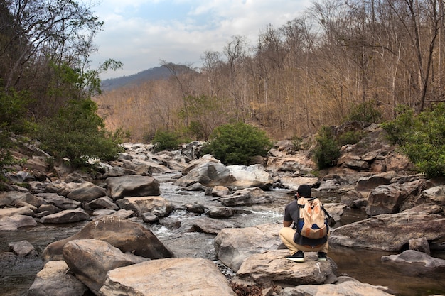 Hiker bending down on stone