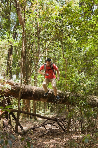 Hiker climbing over tree trunk