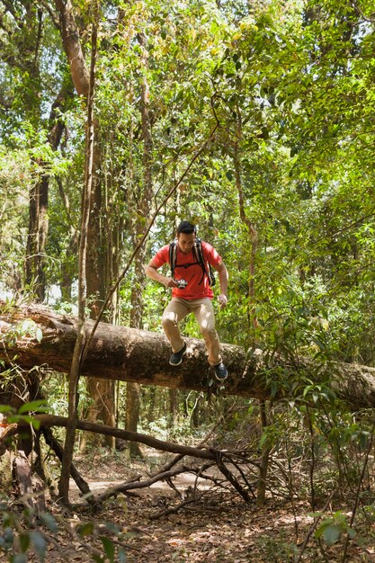 Hiker climbing over tree trunk