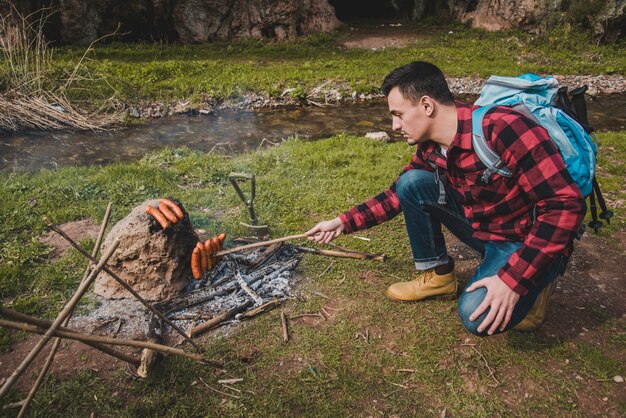 Hiker cooking sausages