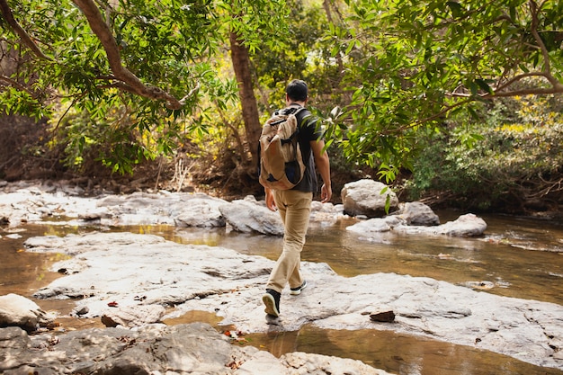 Hiker crossing river in nature