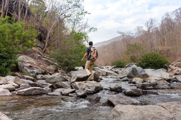 Бесплатное фото Хайкер пересекает реку на камнях