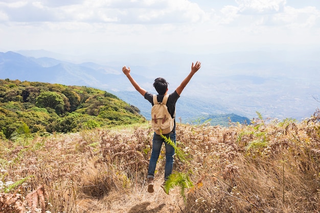 Free photo hiker raising arms towards the sky