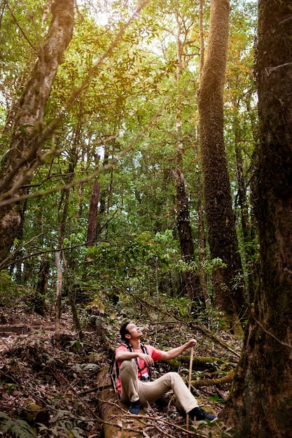 Hiker sitting on a hill in jungle and looking above