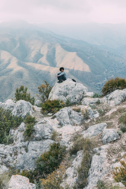 Foto gratuita viandante che si siede sulla roccia