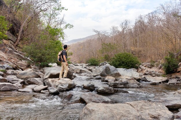 Hiker on stone in wild river