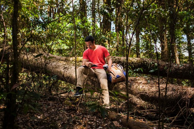 Hiker on tree trunk reading booklet