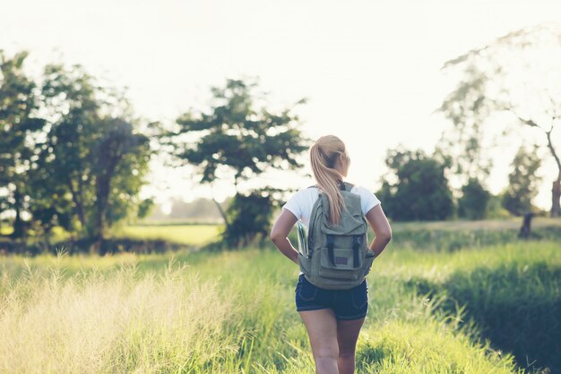 Hiking woman with backpack walking on a gravel road