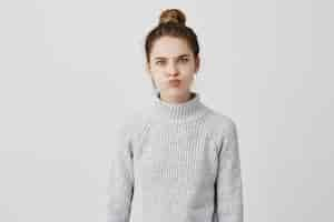 Free photo hilarious caucasian girl with trendy hairstyle blowing her cheeks and frowning forehead. persistant woman requiring attention grimacing being sassy. emotions concept