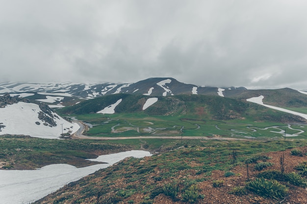 Hills half covered with snow in cloud day