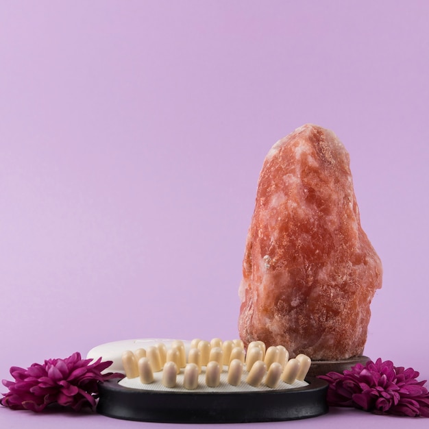 ヒマラヤのピンクの岩塩;マッサージブラシと紫色の背景に花