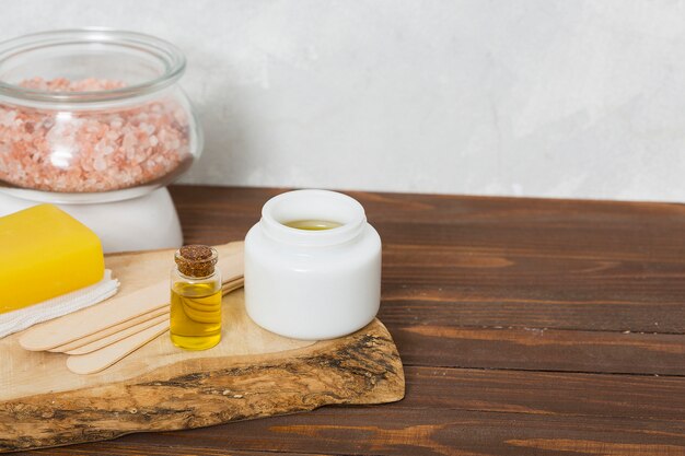 Himalayan rock salt in glass jar; wax wooden sticks; honey; herbal yellow soap and essential oil bottle on table