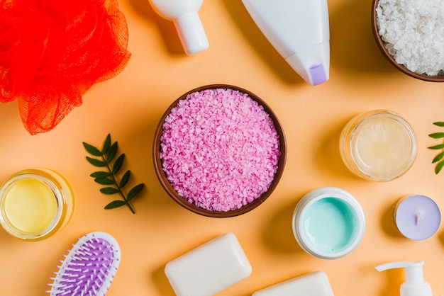 Himalayan salt with cosmetics products on colored background