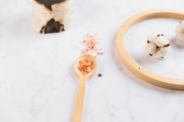 Free photo himalayan salt on wooden spoon with raw cotton ball