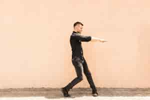 Free photo hip-hop male dancer dancing in front of wall