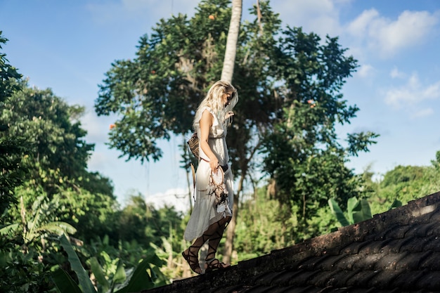 hippie girl with long blond hair in a dress on the roof.