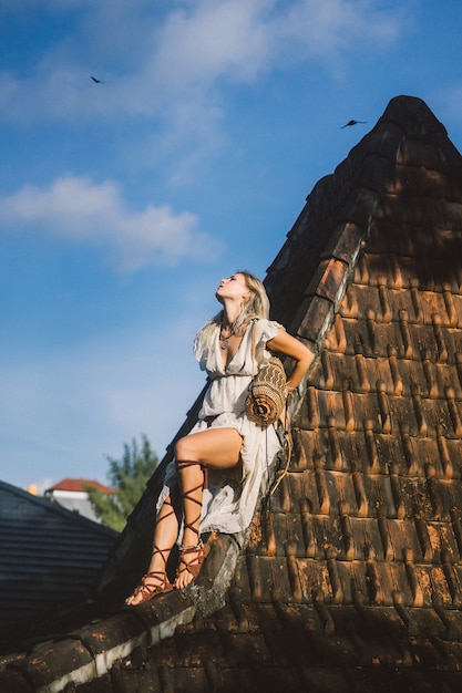 hippie girl with long blond hair in a dress on the roof.