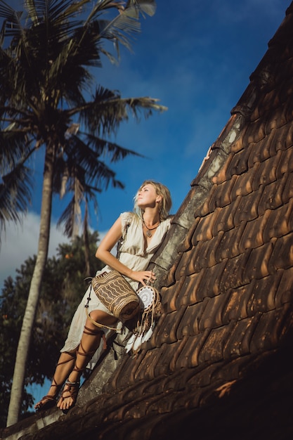 hippie girl with long blond hair in a dress on the roof.