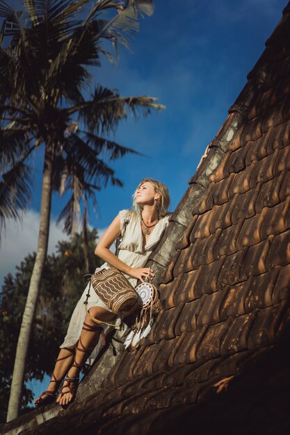 hippie girl with long blond hair in a dress on the roof.