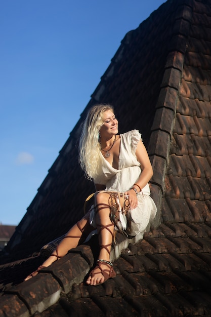 hippie girl with long blond hair in a dress on the roof.