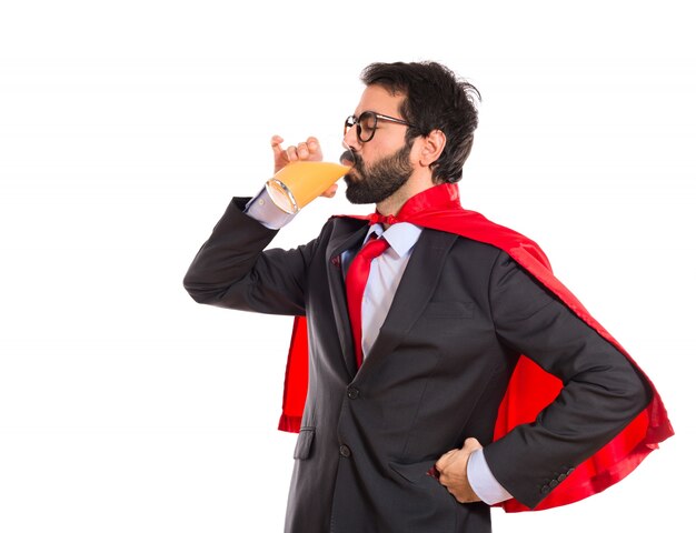 Hipster businessman dressed like superhero drinking orange juice