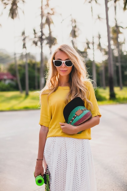 Free photo hipster cool woman with skate board and cap posing smiling on vacation