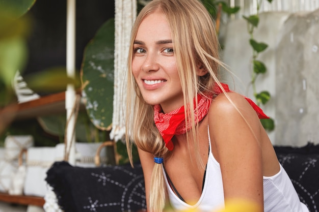 Ragazza hipster con bandana sul collo pone nella caffetteria