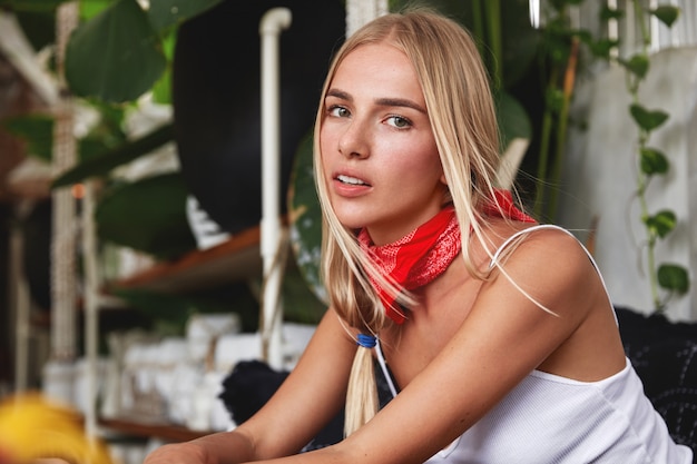 Hipster girl with bandana on neck poses in cafe