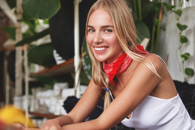 Hipster girl with bandana on neck poses in cafe