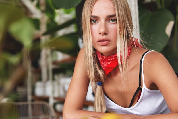 Ragazza hipster con bandana sul collo pone nella caffetteria